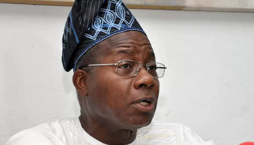 Homme portant un boubou blanc et un bonnet traditionnel bleu parlant en regardant vers la droite