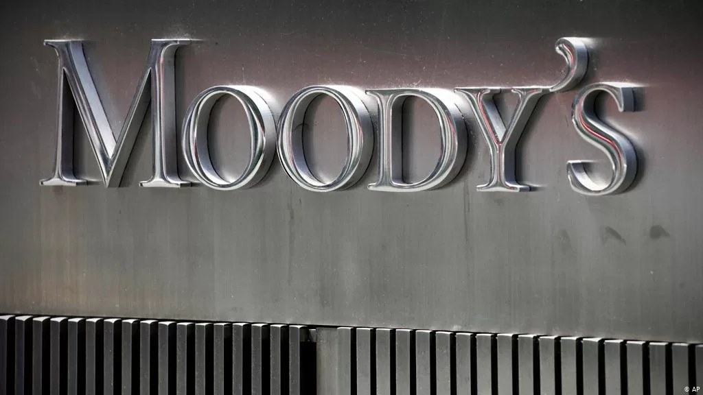 Logo métallique de Moody’s fixé sur une façade grise avec des lames noires en dessous