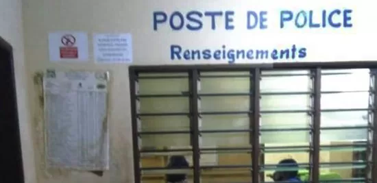 Guichet fermé d’un poste de police avec deux personnes visibles à l’intérieur derrière une grille.