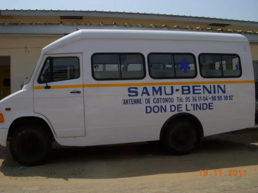 Véhicule blanc marqué SAMU-BENIN antenne de Cotonou don de l'Inde garé devant un bâtiment beige