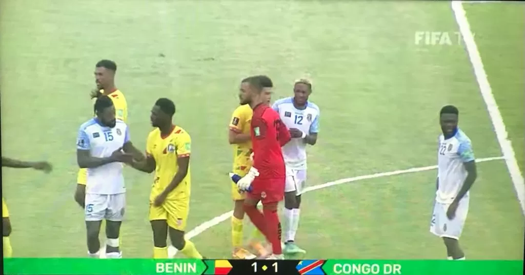 Des joueurs de deux équipes de football discutent et se serrent la main au milieu du terrain pendant un match à égalité 1-1