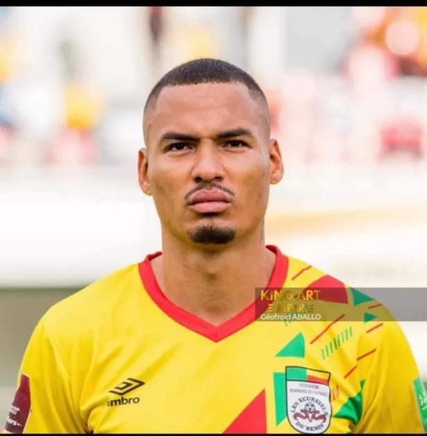 Homme en maillot jaune vif orné de rouge et vert, regard sérieux face à l’objectif sur un fond flou de stade