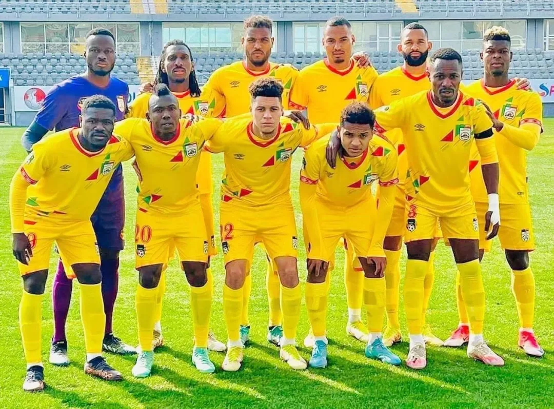 Onze joueurs de football en tenue jaune posent sur un terrain, alignés en deux rangées, avant un match