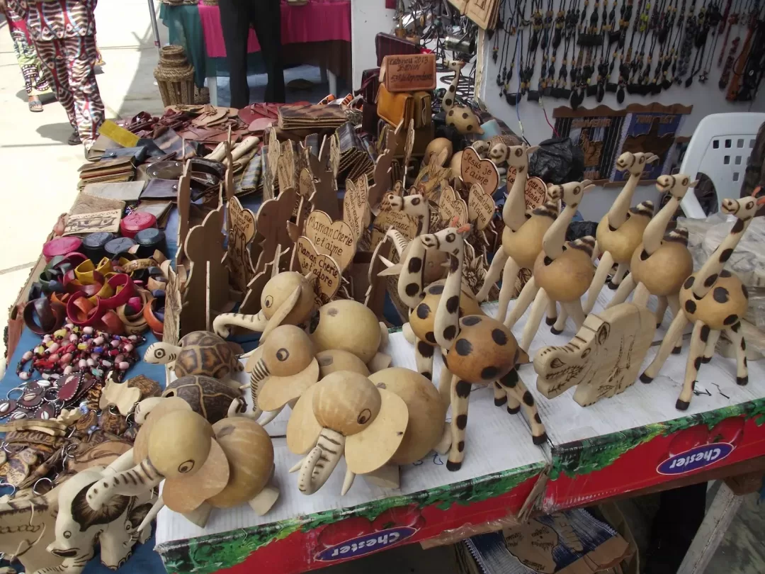 Vêtements colorés et étalage d objets artisanaux en bois et cuir aux motifs animaux et messages divers