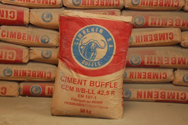 Sacs de ciment empilés avec un sac en avant portant l'inscription CIMENT BUFFLE 50 kg fabriqué au Bénin