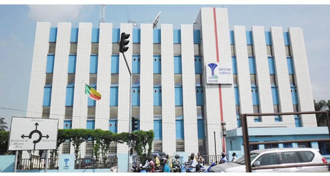 Bâtiment administratif de plusieurs étages avec un drapeau tricolore soutenu par une barrière bleue au premier plan