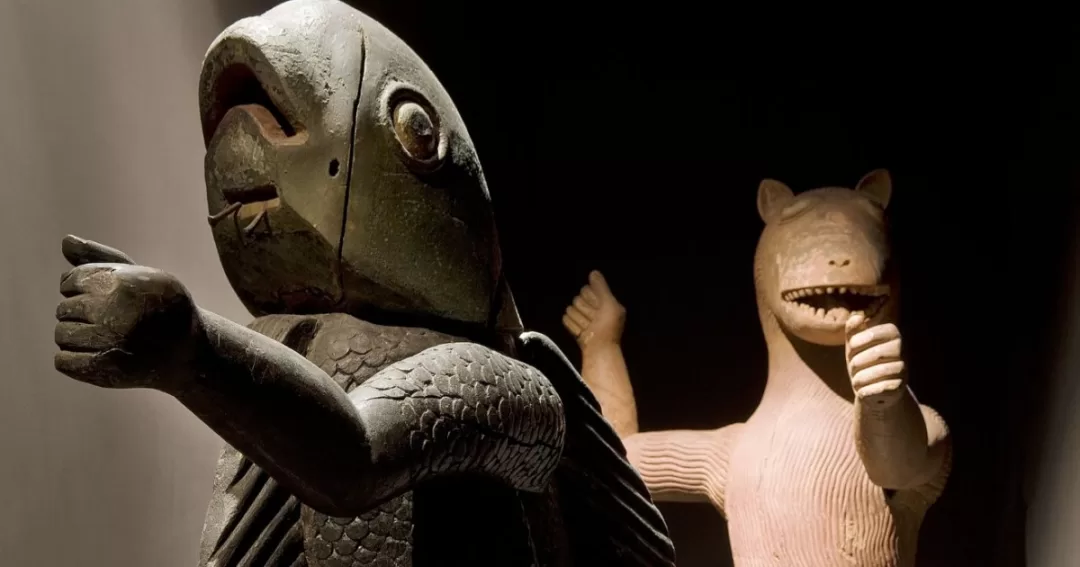 Deux sculptures anciennes en bois représentant des figures animales éclairées dans une pièce sombre