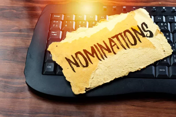 Carte déchirée avec le mot nominations posée sur un clavier d'ordinateur noir sur fond bois