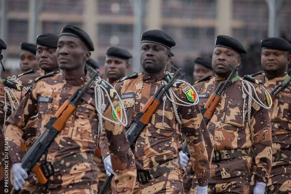 Des hommes en uniforme camouflage marron et noir avec bérets noirs défilent en rangs serrés dans la rue