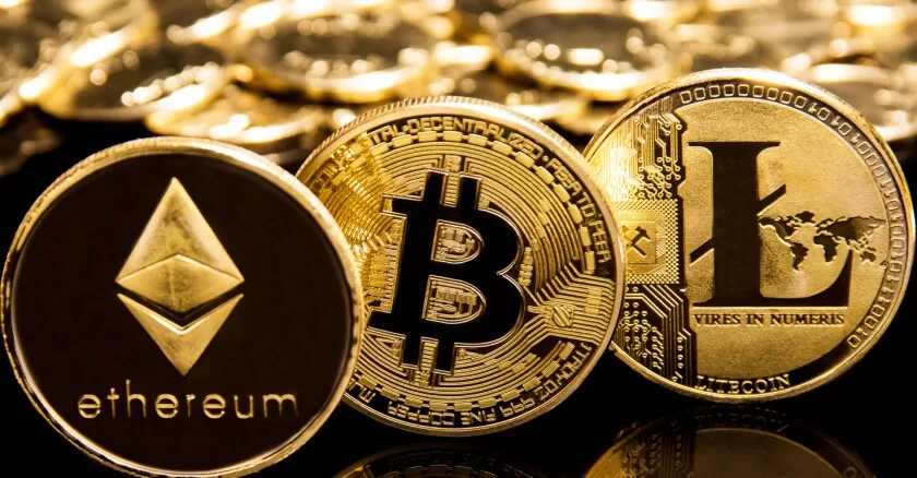 Pièces dorées représentant les symboles des cryptomonnaies Ethereum, Bitcoin et Litecoin alignées sur un fond flou similaire