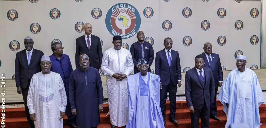 Onze hommes posant en groupe devant un mur orné de logos circulaires et un grand logo central avec une carte de l'Afrique
