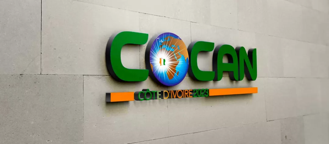 Logo vert et bleu avec un globe terrestre et le texte Côte d'Ivoire 2023 sur un mur beige clair