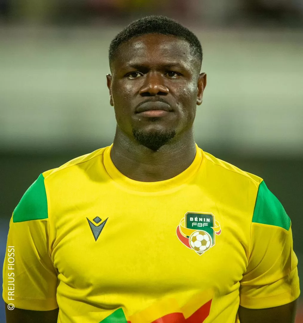 Homme portant un maillot de football jaune orné d’un écusson vert et blanc avec un ballon et le texte «BÉNIN FBF