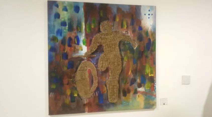 Peinture colorée avec silhouette en relief d'une personne courant derrière une roue sur un mur blanc d'exposition