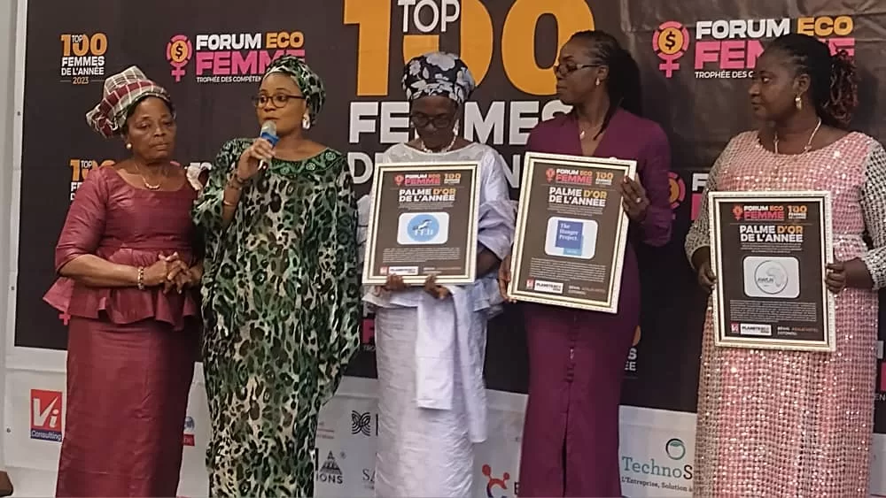 Cinq femmes debout, trois tenant des cadres de récompense, le mur arrière affiche Forum Eco Femme et Top 100 Femmes