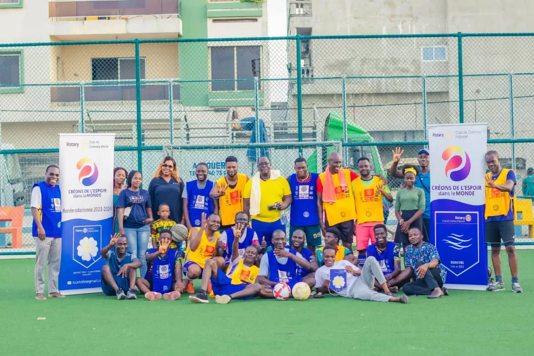 Groupe de personnes posant sur un terrain de football avec deux banderoles Rotary de chaque côté