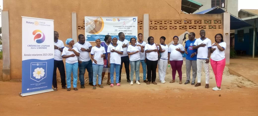 Un groupe de femmes en T-shirts blancs et pantalons divers posant devant un mur avec deux kakemonos de sensibilisation au dépistage du cancer.