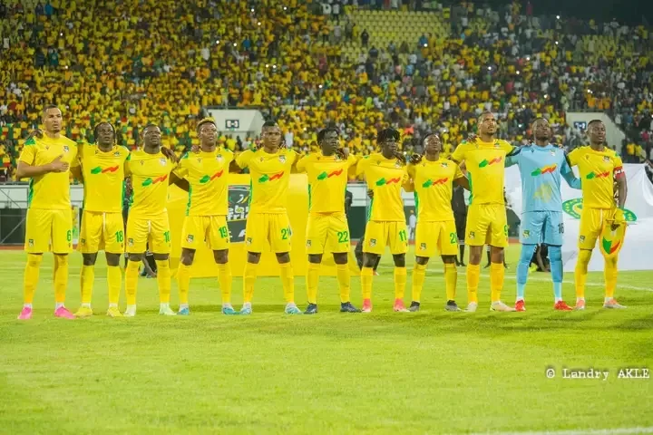 Onze joueurs de football en tenue jaune alignés bras dessus bras dessous sur le terrain avant le match