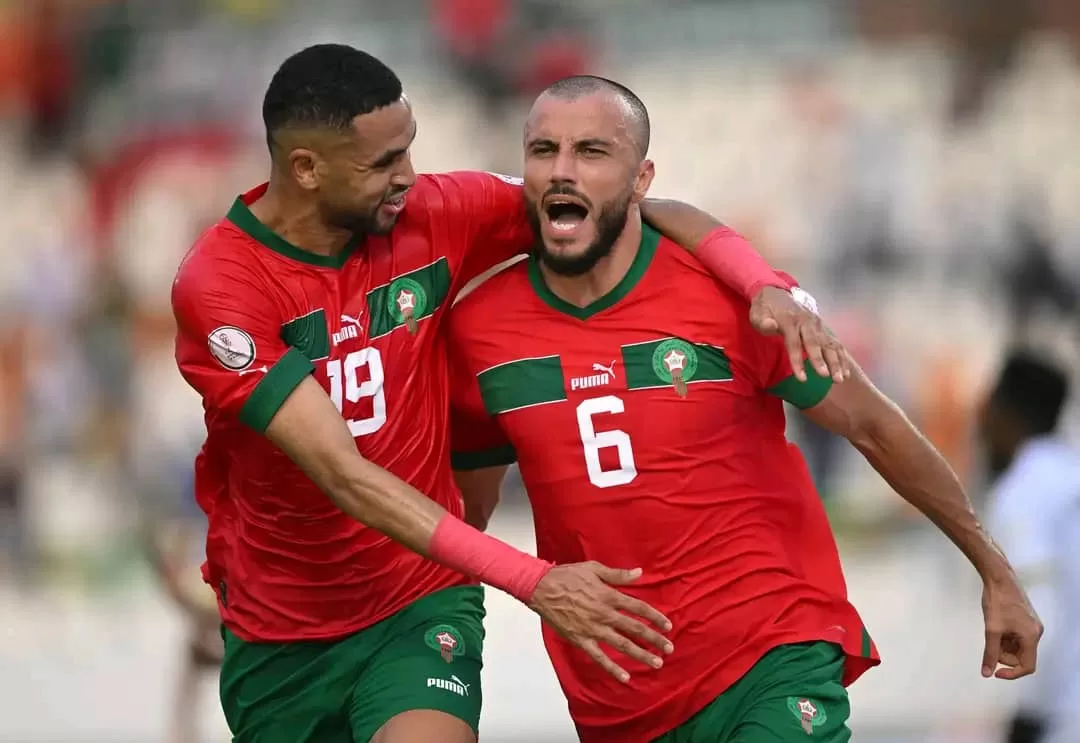 Deux joueurs en maillots rouges célèbrent ensemble un but lors d’un match de football