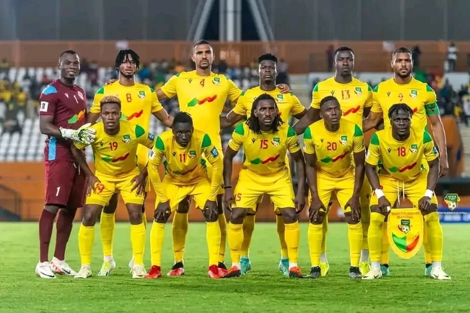 Équipe de football posant sur le terrain avant un match avec un joueur tenant un fanion bordé jaune et vert
