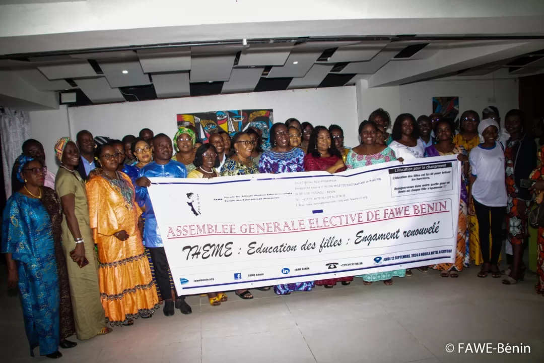 Groupe de femmes tenant une grande banderole sur le thème de l’éducation des filles dans une salle intérieure