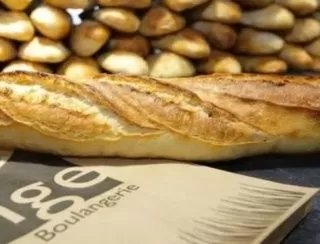 Plusieurs baguettes de pain posées sur un sac en papier dans une boulangerie