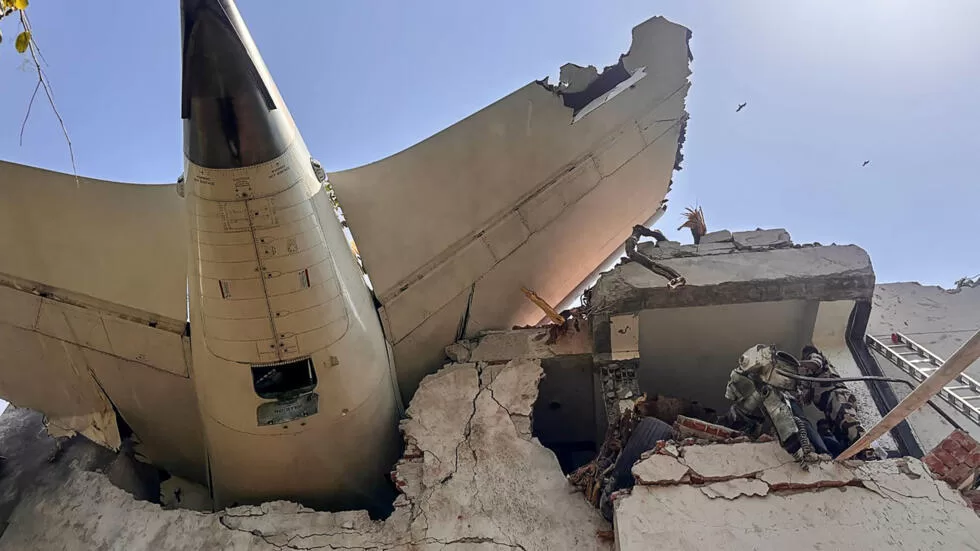 Partie arrière d’un avion encastrée dans un immeuble effondré avec des personnes sur les décombres