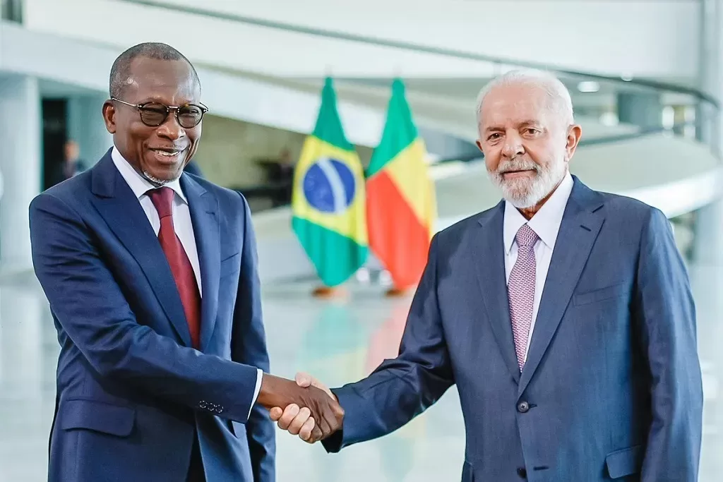 Deux hommes en costume se serrent la main devant les drapeaux du Brésil et d un pays africain