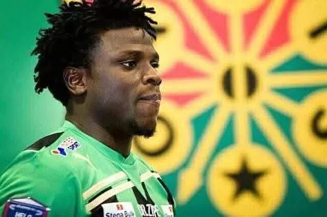 Jeune homme portant un maillot de football vert devant un drapeau coloré flou en arrière-plan