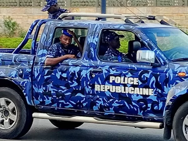 Quatre policiers en uniforme bleu dans un véhicule tout-terrain bleu camouflé marqué Police Républicaine