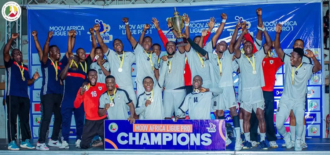 Joueurs d une équipe de handball en tenue sportive brandissant une coupe sur un podium avec une banderole champions et un fond d écran bleu