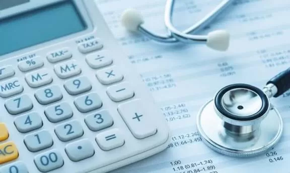 Une calculatrice et un stéthoscope posés sur un document financier détaillant des chiffres et des pourcentages