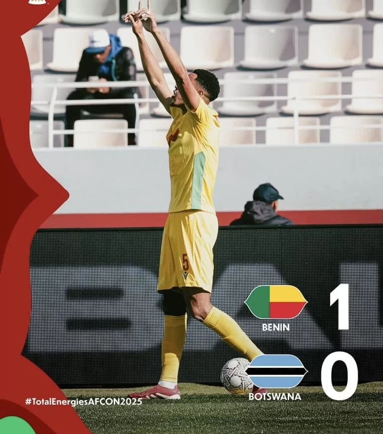 Un joueur en maillot jaune lève les bras en signe de victoire près d un ballon de football sur le terrain
