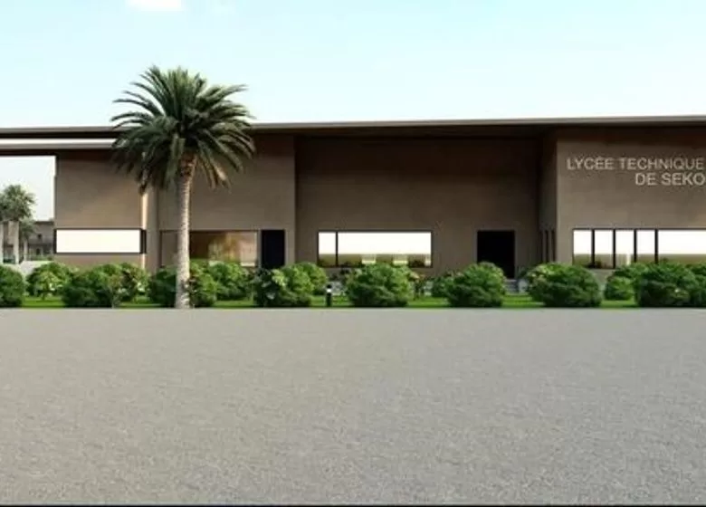 Façade d un bâtiment moderne avec des fenêtres rectangulaires et une haie devant sous un ciel clair