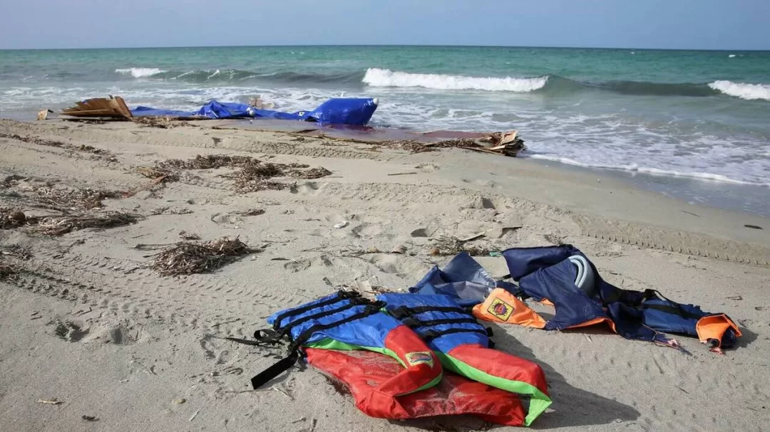 Vêtements et gilets de sauvetage abandonnés sur le sable près de la mer agitées avec des vagues qui déferlent sur la plage