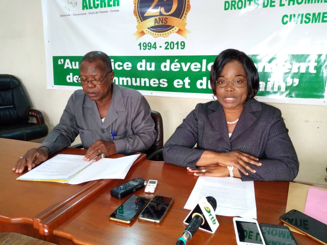 Deux personnes assises à une table avec des documents et micros devant un panneau commémorant 25 ans d'une organisation