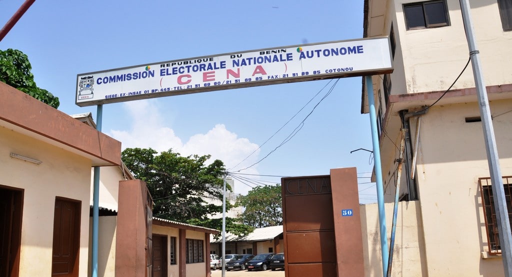 Entrée principale d’un bâtiment avec une enseigne indiquant Commission Électorale Nationale Autonome sous un ciel bleu clair
