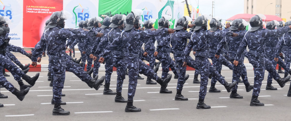 Des agents en uniformes bleus et casques participent à une parade militaire en levant la jambe en cadence