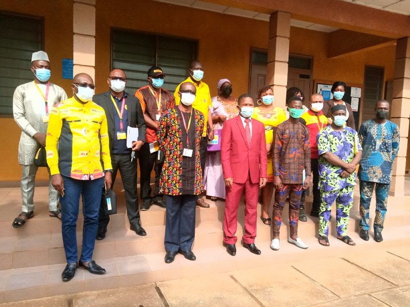 Groupe de personnes posant dehors sur des marches devant un bâtiment, toutes portant un masque sanitaire