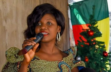 Femme parlant au micro devant un drapeau et un sapin de Noël décoré