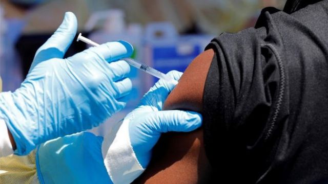 Une personne reçoit une injection vaccinante dans le bras par un professionnel portant des gants médicaux