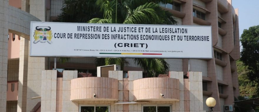 Panneau officiel avec texte du ministère de la justice et législation sur un bâtiment moderne entouré de palmiers
