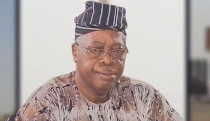 Homme portant un boubou africain et un bonnet rayé posant devant un fond clair flou