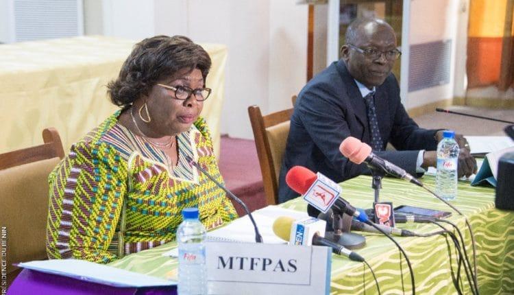 Deux personnes assises à une table avec plusieurs micros posés devant elles lors d'une réunion formelle