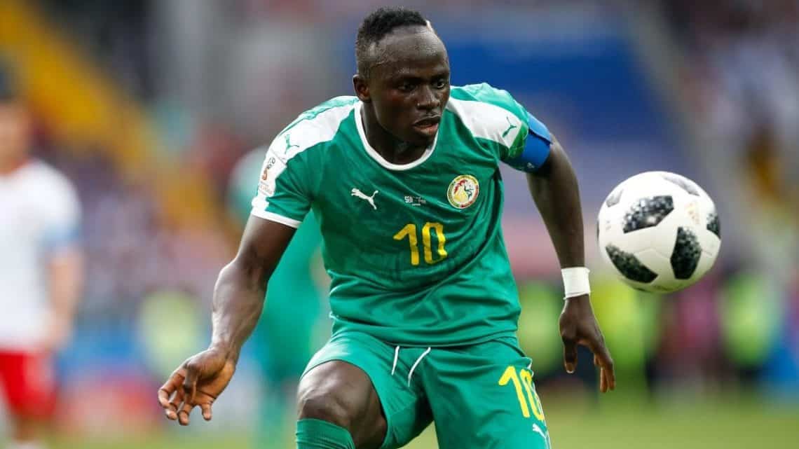 Joueur en maillot vert avec numéro 10 contrôlant un ballon de football noir et blanc en plein match