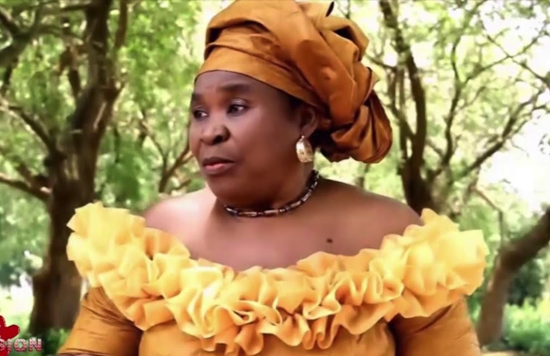 Femme habillée en tenue traditionnelle jaune avec un foulard assorti dans un cadre verdoyant en extérieur