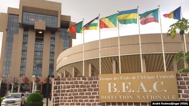 Façade d’un bâtiment administratif avec plusieurs drapeaux africains et un panneau BEAC direction nationale devant l’entrée