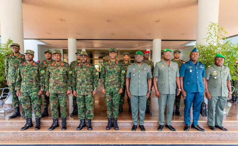 Quinze militaires en tenue posant sur des marches devant un bâtiment sous un auvent avec des colonnes blanches