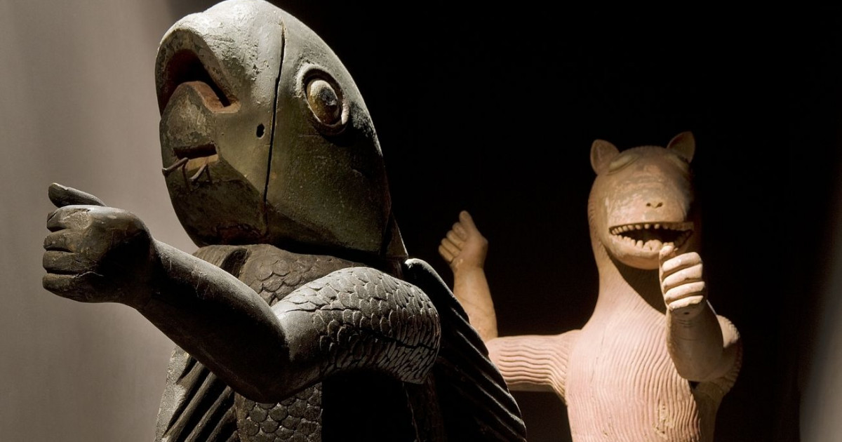 Deux sculptures anciennes en bois représentant des figures animales éclairées dans une pièce sombre