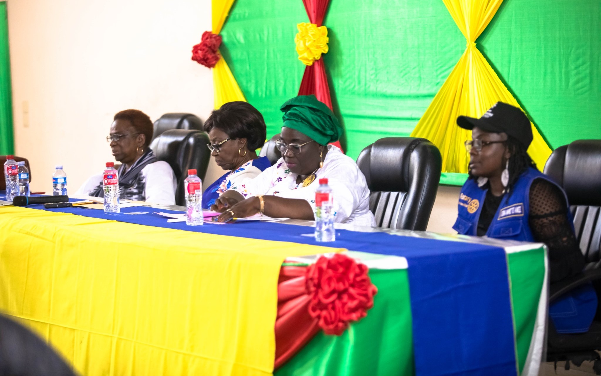 Quatre femmes assises derrière une table décorée aux couleurs vives dans une salle ornée de tissus colorés